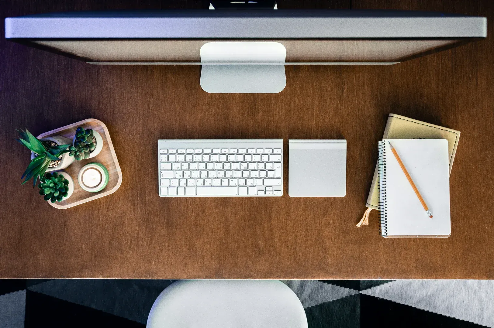 Top-down view of a minimalist workspace with keyboard, notebook, and planner, representing organized financial structure, productivity systems, and disciplined creative workflow.