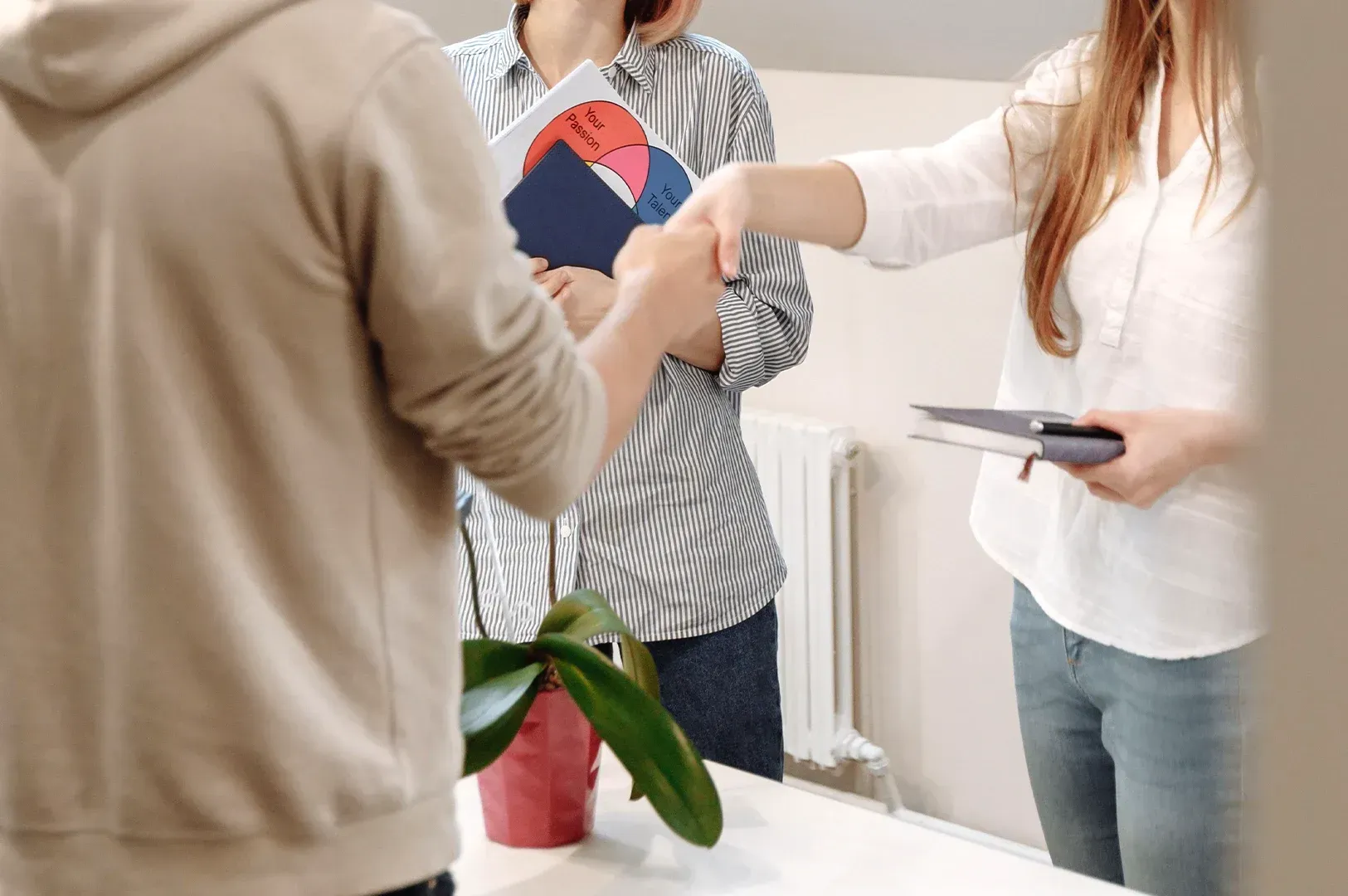 Professional collaboration scene featuring a handshake and notebooks, emphasizing human connection, passion, and intentional teamwork in the creative process rather than automated production.