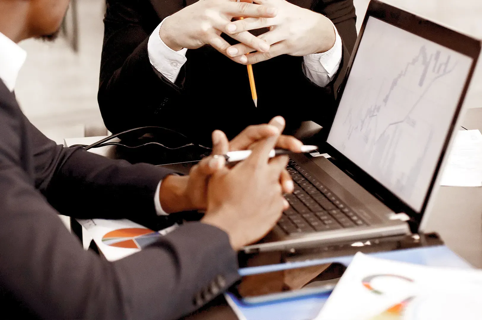 Two colleagues in formal suits reviewing data on a laptop and documents, highlighting the steady temperament and professional alignment needed in business.