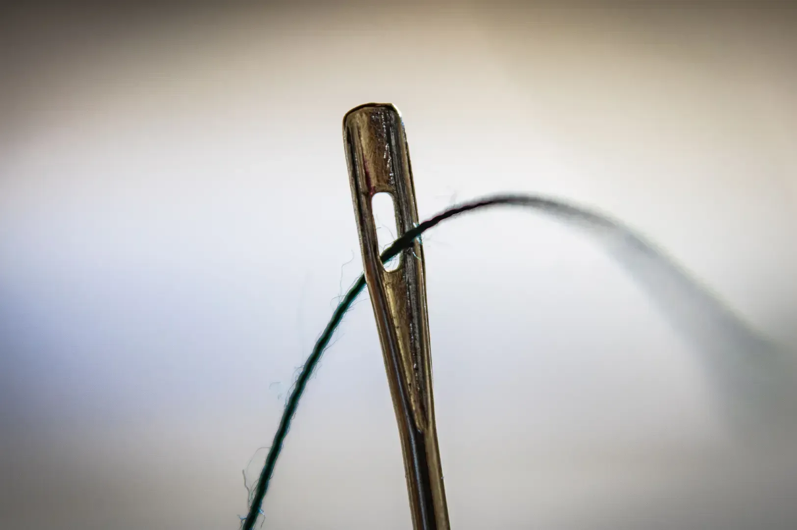 A candid shot of a needle and thread, serving as a poignant symbol for the delicate art of mending, forgiveness, and the precise process of beginning again.