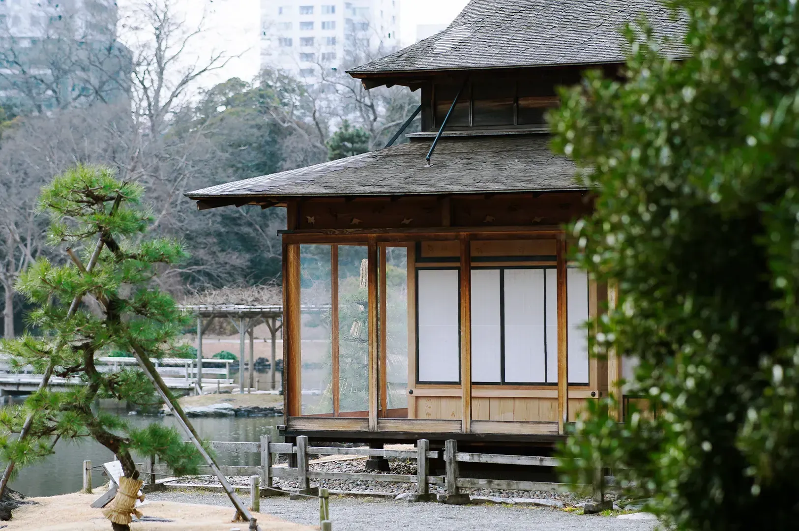 A traditional wooden Japanese teahouse set within a serene garden, serving as a contemplative destination that rewards the patient traveler who uses slow, intentional movement to engage with the city.