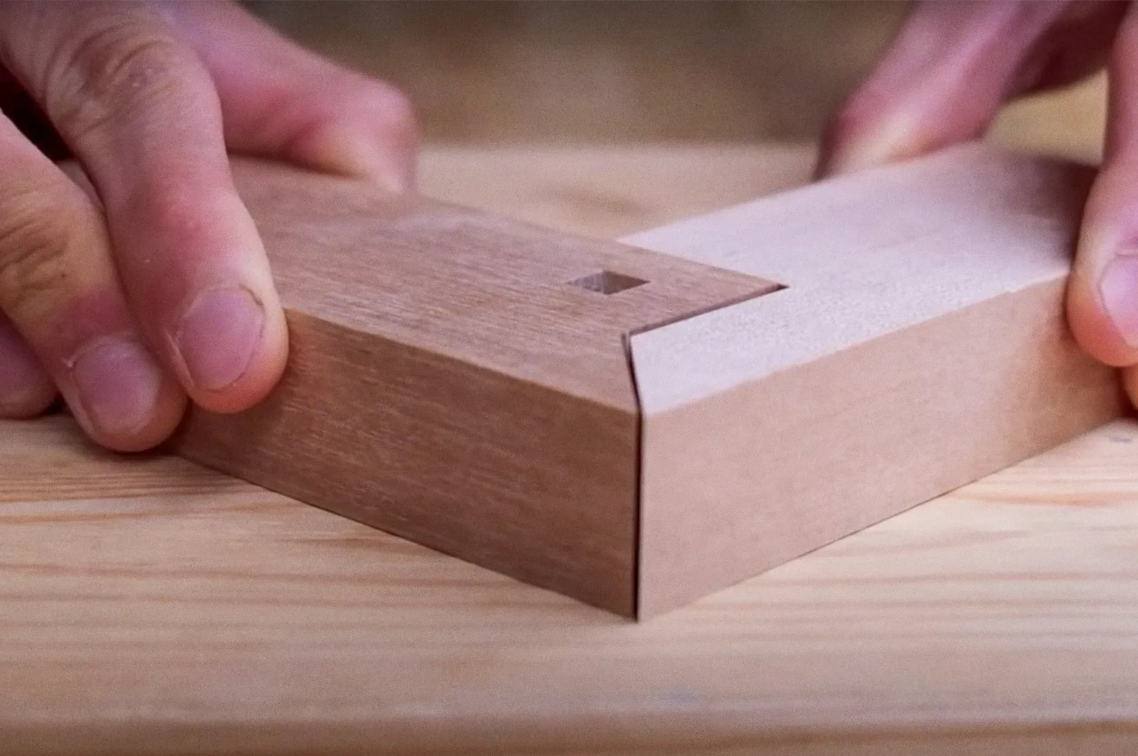 Close-up macro shot at eye-level angle of hands aligning precision Japanese woodworking joinery, showcasing minimalist craftsmanship and focus on simplicity in design.