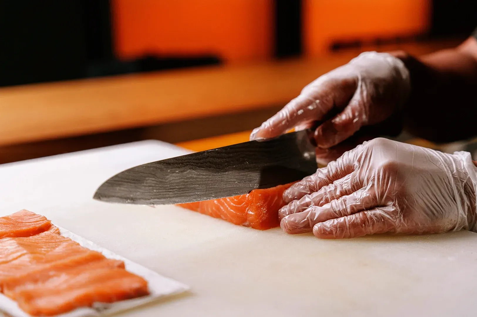 A close-up of hands wearing food-safe gloves skillfully slicing fresh salmon on a white cutting board, symbolizing the meditative, rhythmic nature of professional craft and morning preparation rituals.