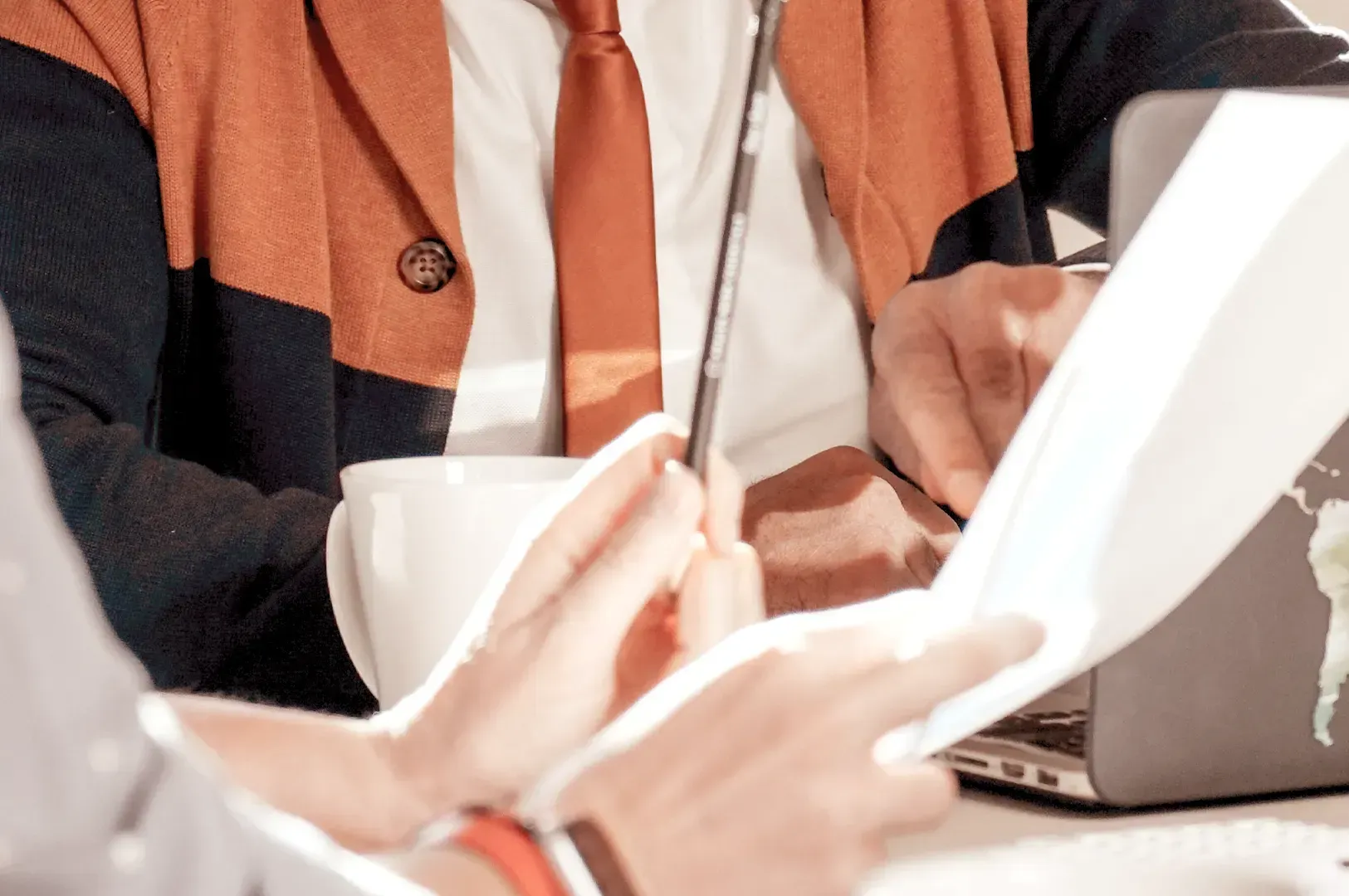 A business team reviewing paperwork and notes over coffee, representing the collaborative dialogue and shared vision of a quiet empire.