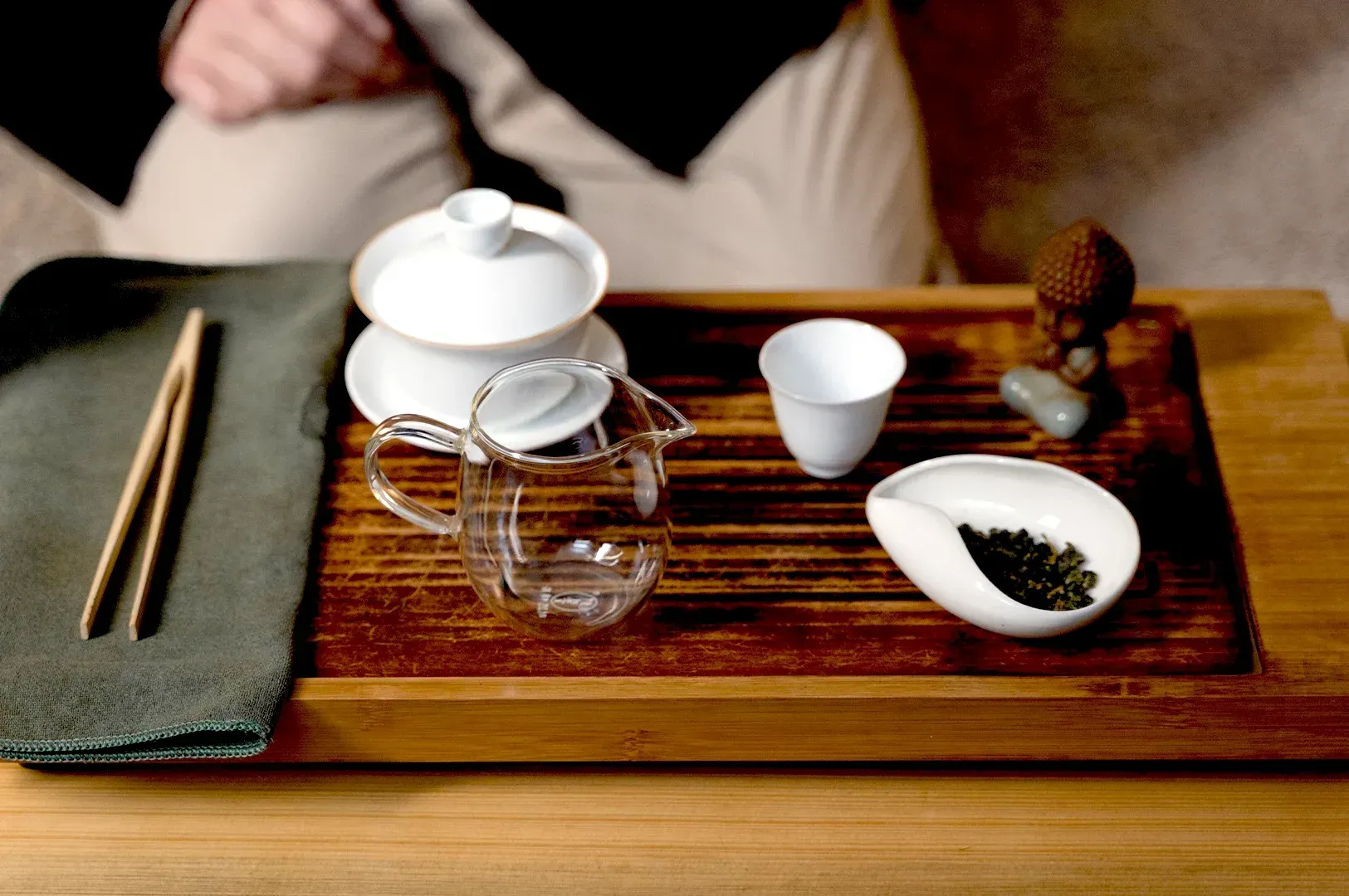 An intimate tea ceremony setup on a wooden tray with handcrafted tea ware and loose leaves, emphasizing the mindful, imperfect details that reveal the real essence of slow living.