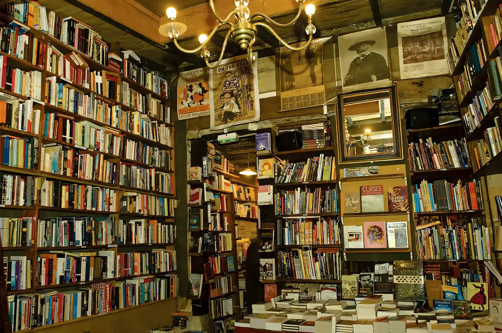 Vintage bookshop interior packed with floor‑to‑ceiling shelves, classic posters, stacked books, and warm ambient lighting.