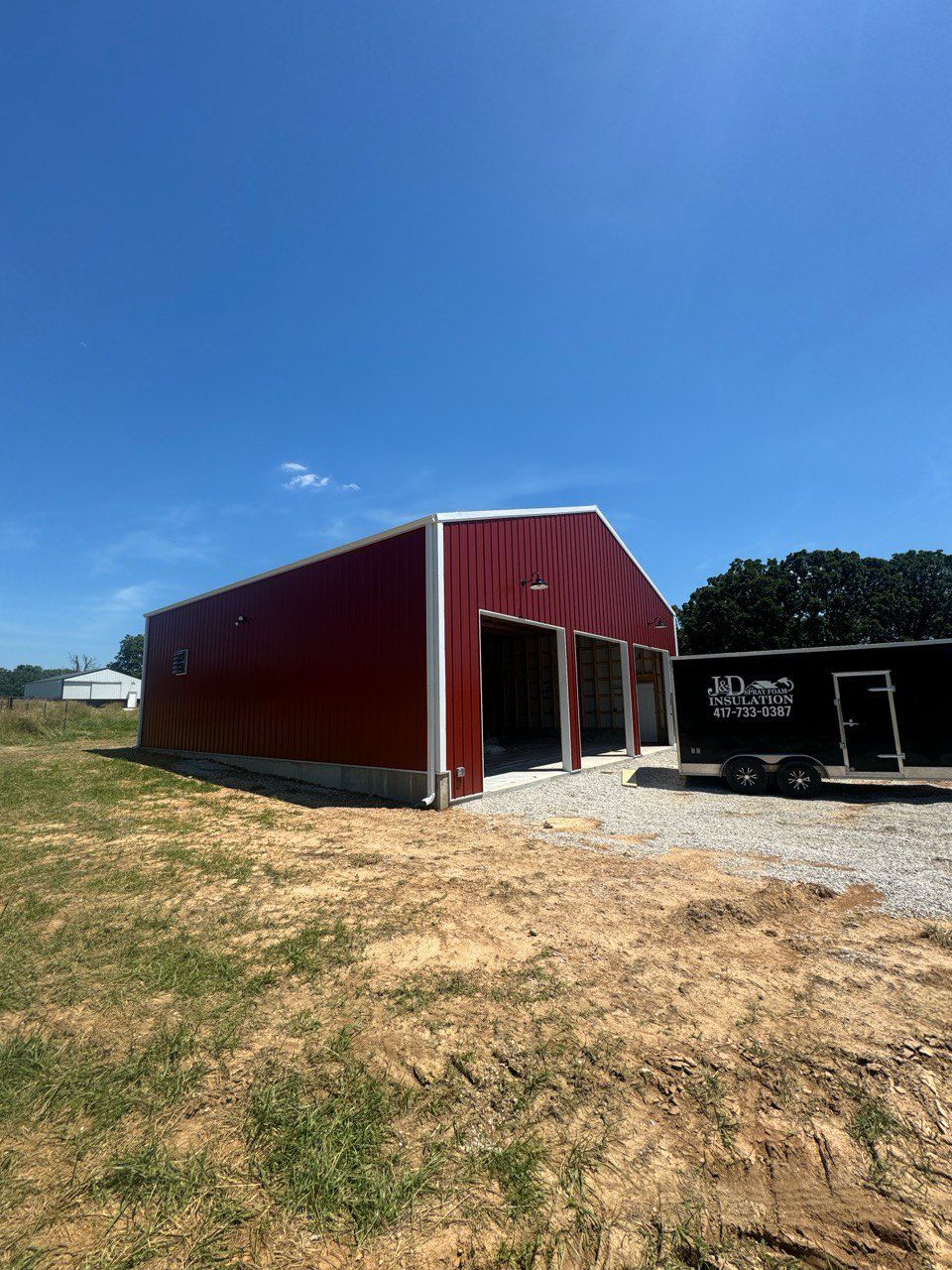 A large red barn is sitting in the middle of a grassy field.