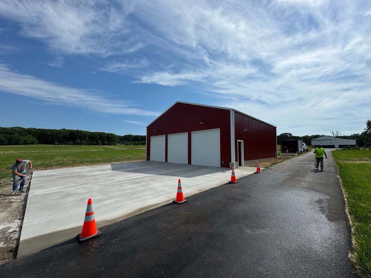 A red barn is being built on the side of a road.