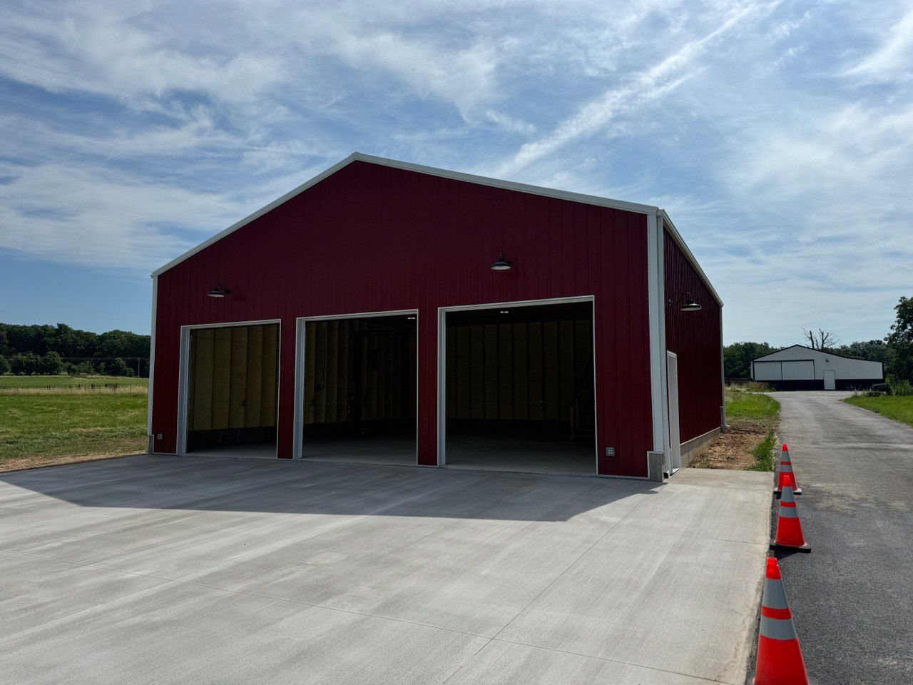 A red building with two doors is sitting on the side of a road.