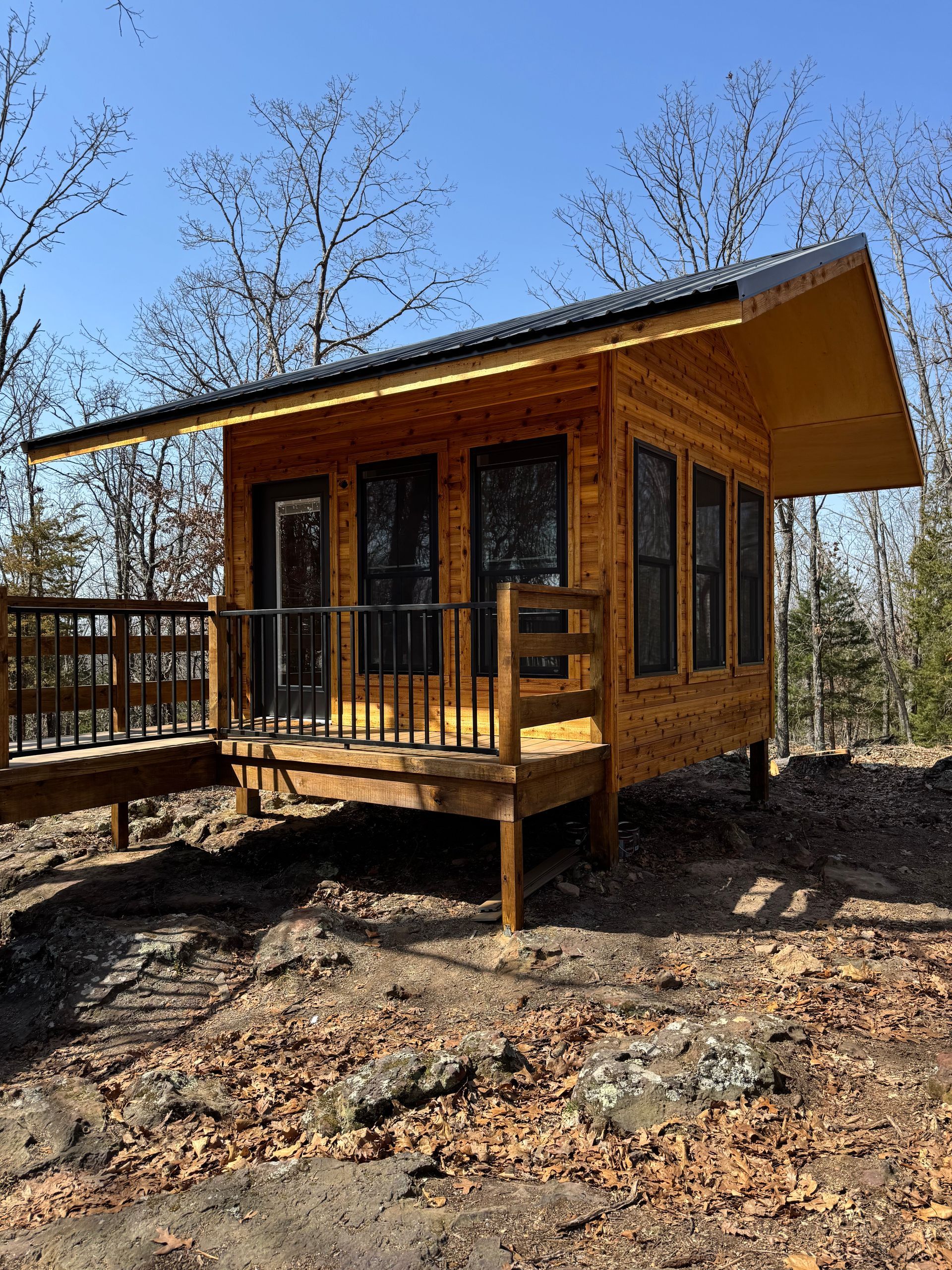 A small wooden cabin with a deck in the woods.