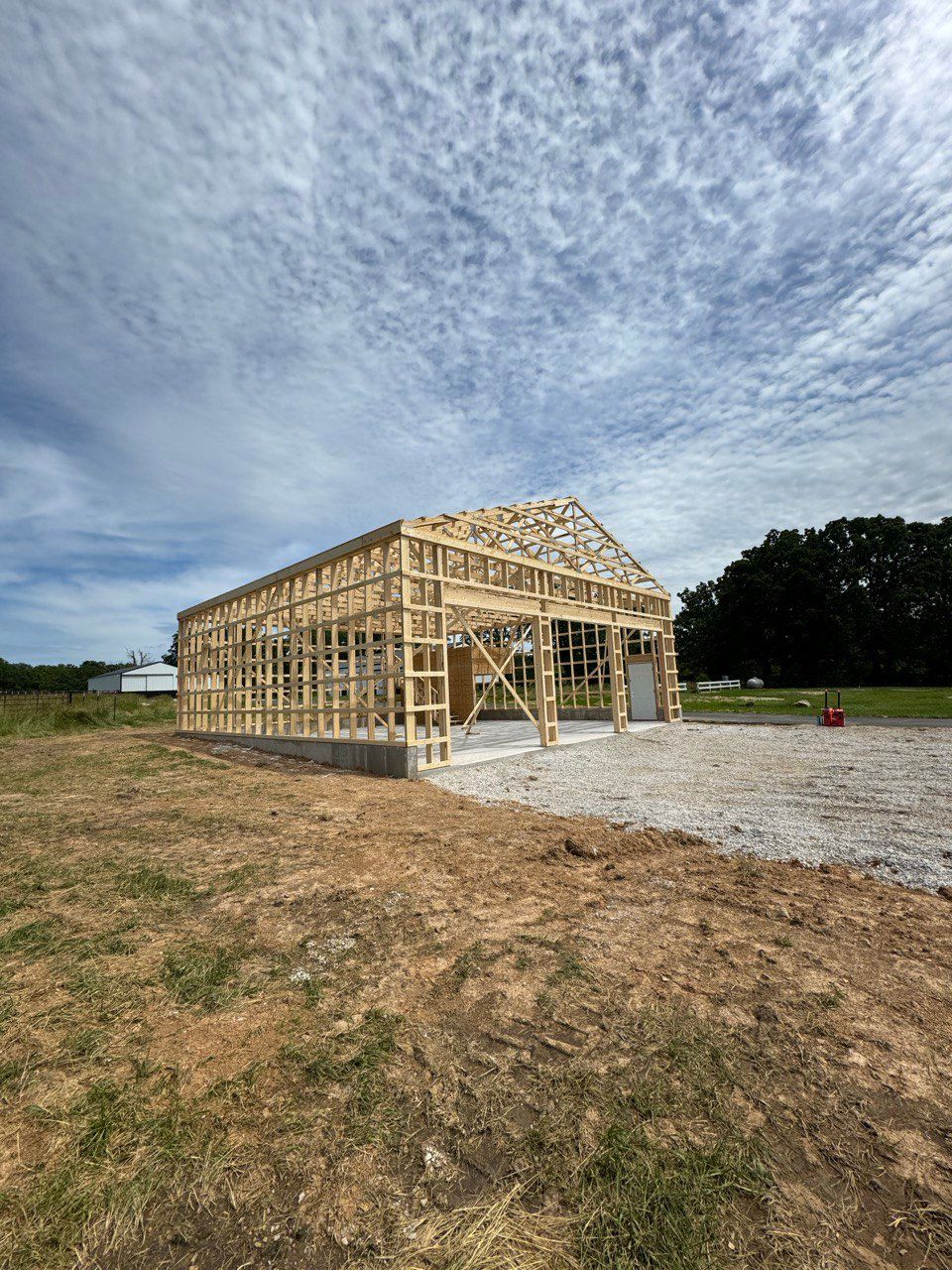 A large wooden building is being built in a field.