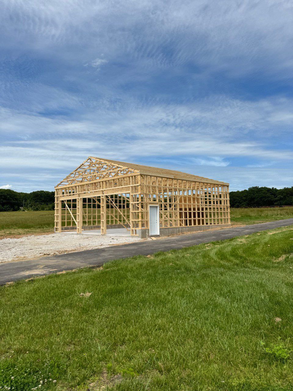 A wooden garage is being built in the middle of a grassy field.