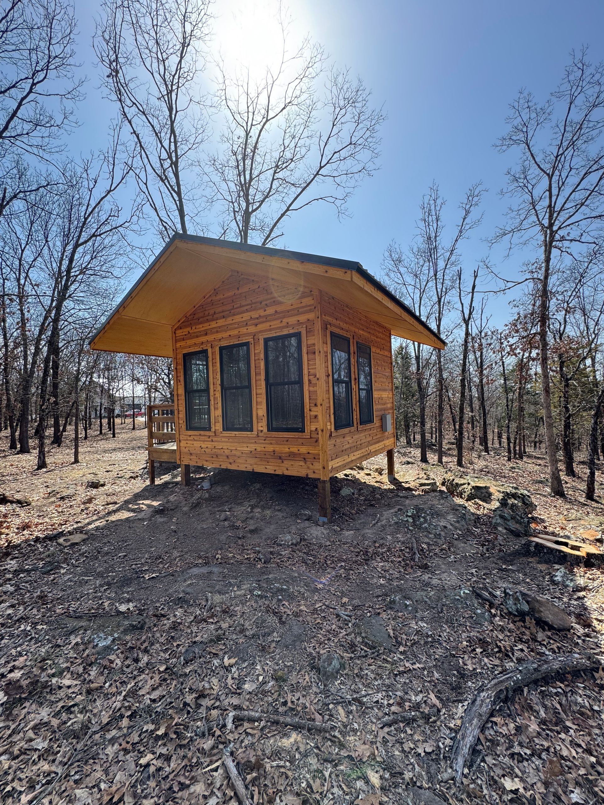 A small wooden cabin is sitting in the middle of a forest.