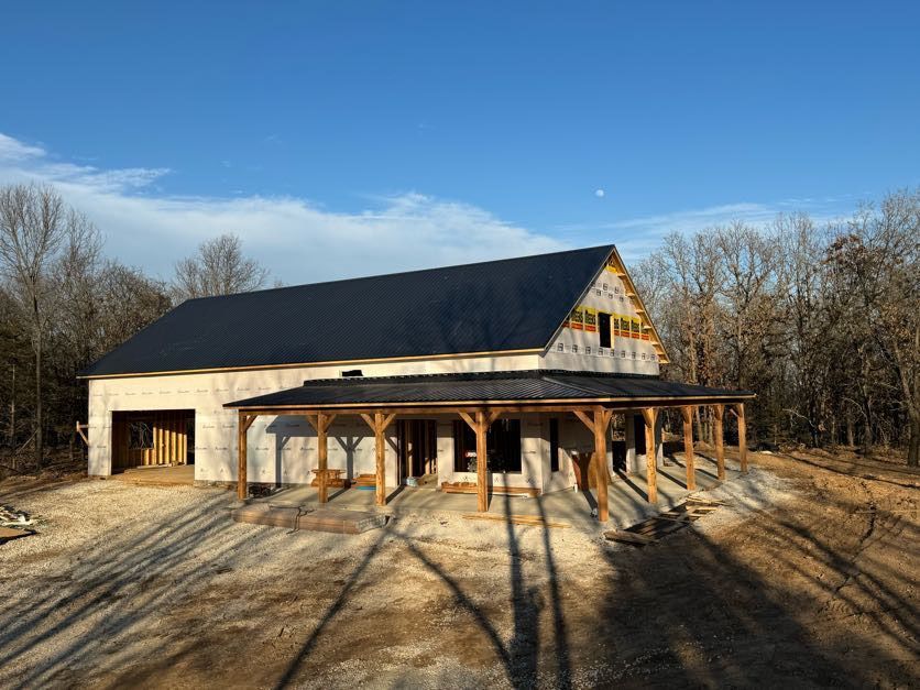 A house under construction with a black roof and a porch.