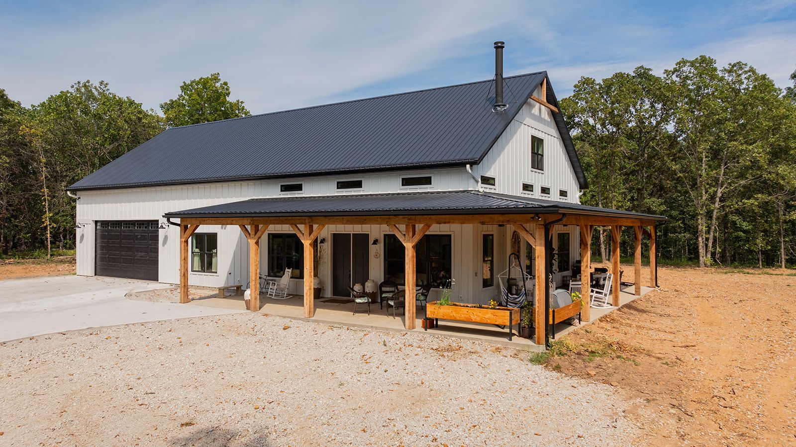 A white house with a black roof and a porch.