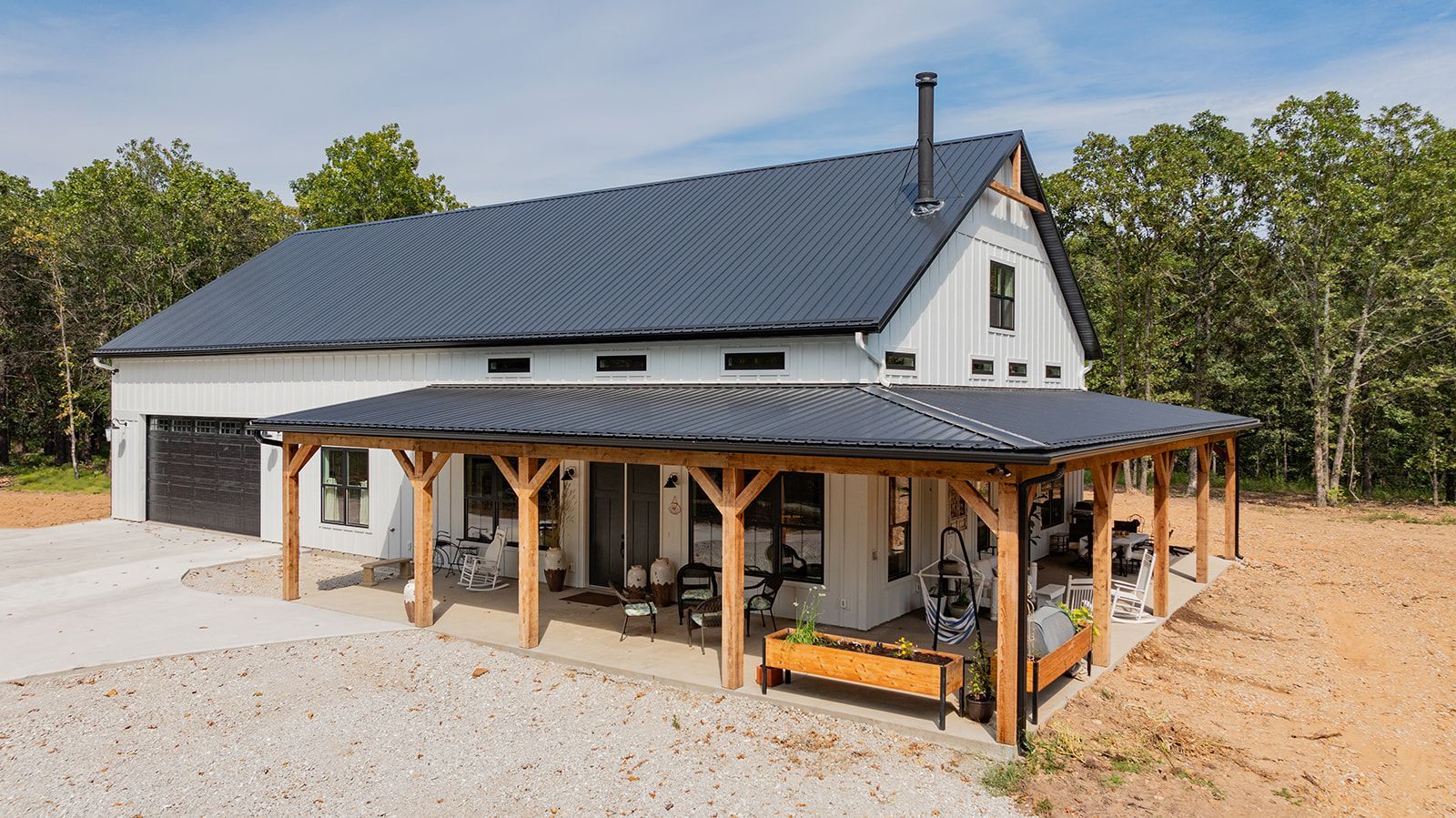 A white house with a black roof and a porch.