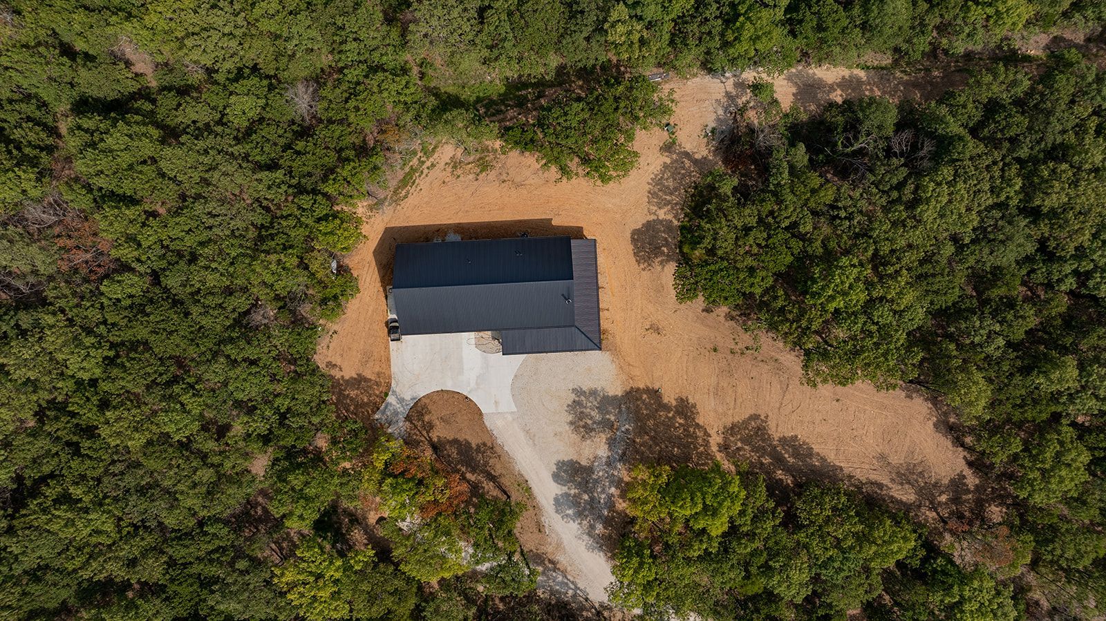 An aerial view of a house in the middle of a forest.