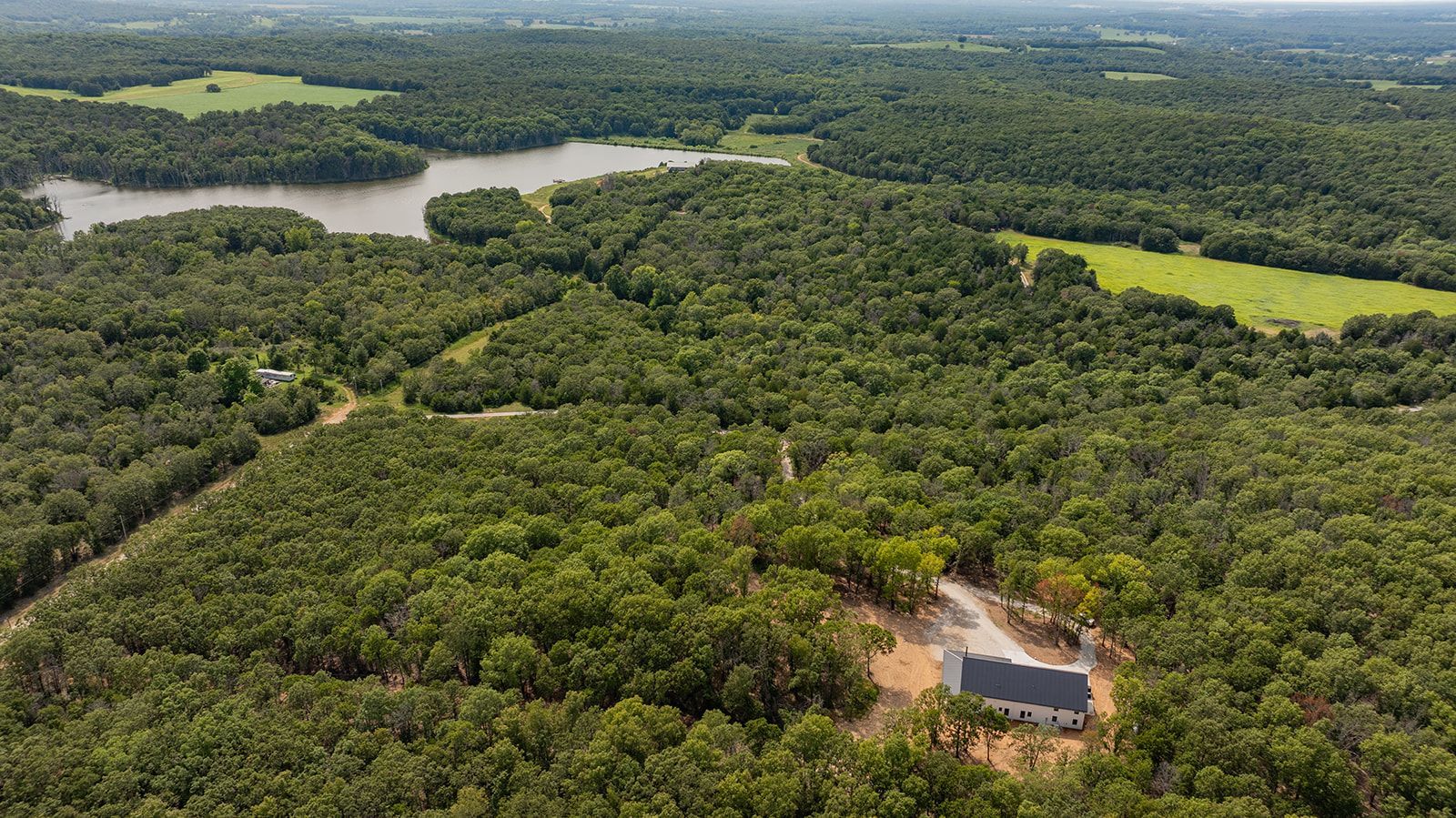 An aerial view of a house surrounded by trees and a lake.