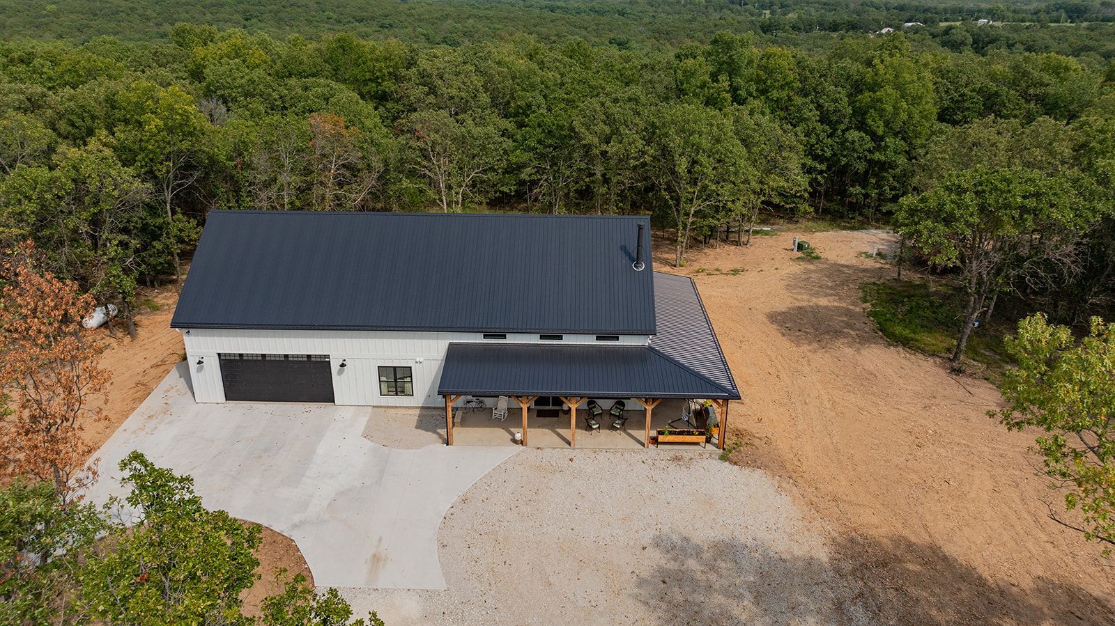 An aerial view of a house in the middle of a forest.