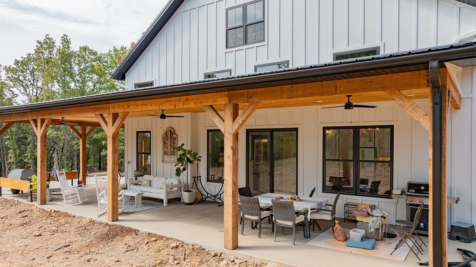 A large white house with a wooden porch and patio furniture.