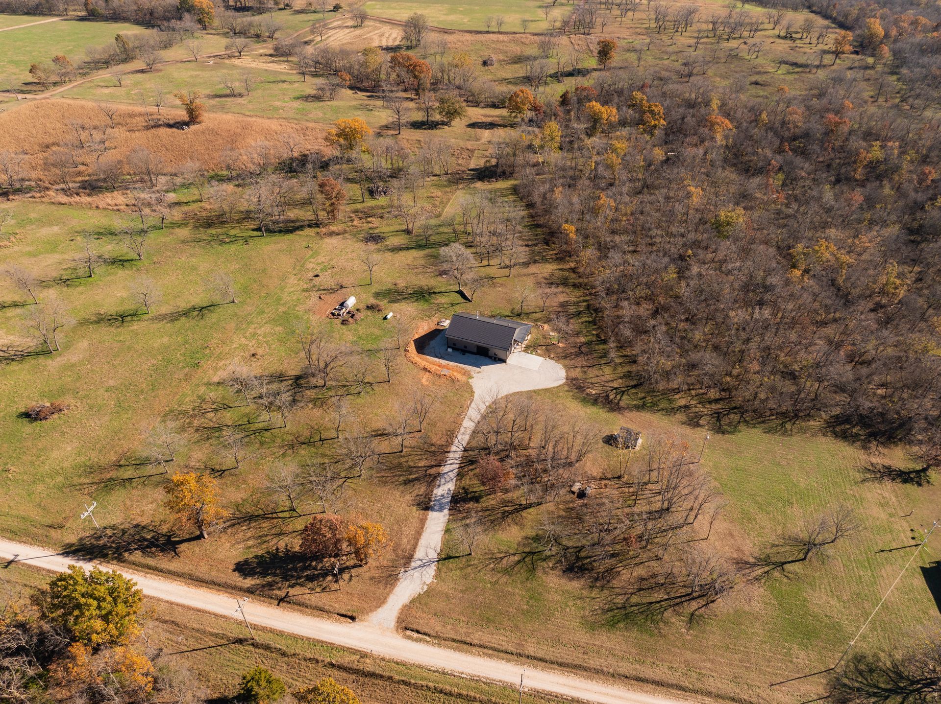 An aerial view of a house in the middle of a field surrounded by trees.