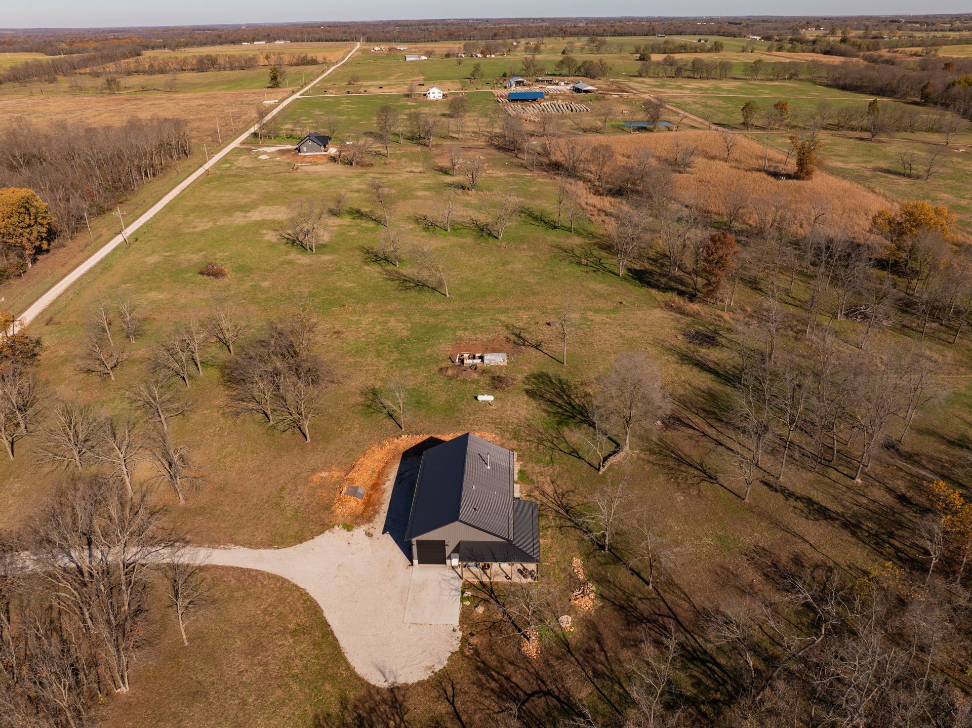 An aerial view of a house in the middle of a field surrounded by trees.