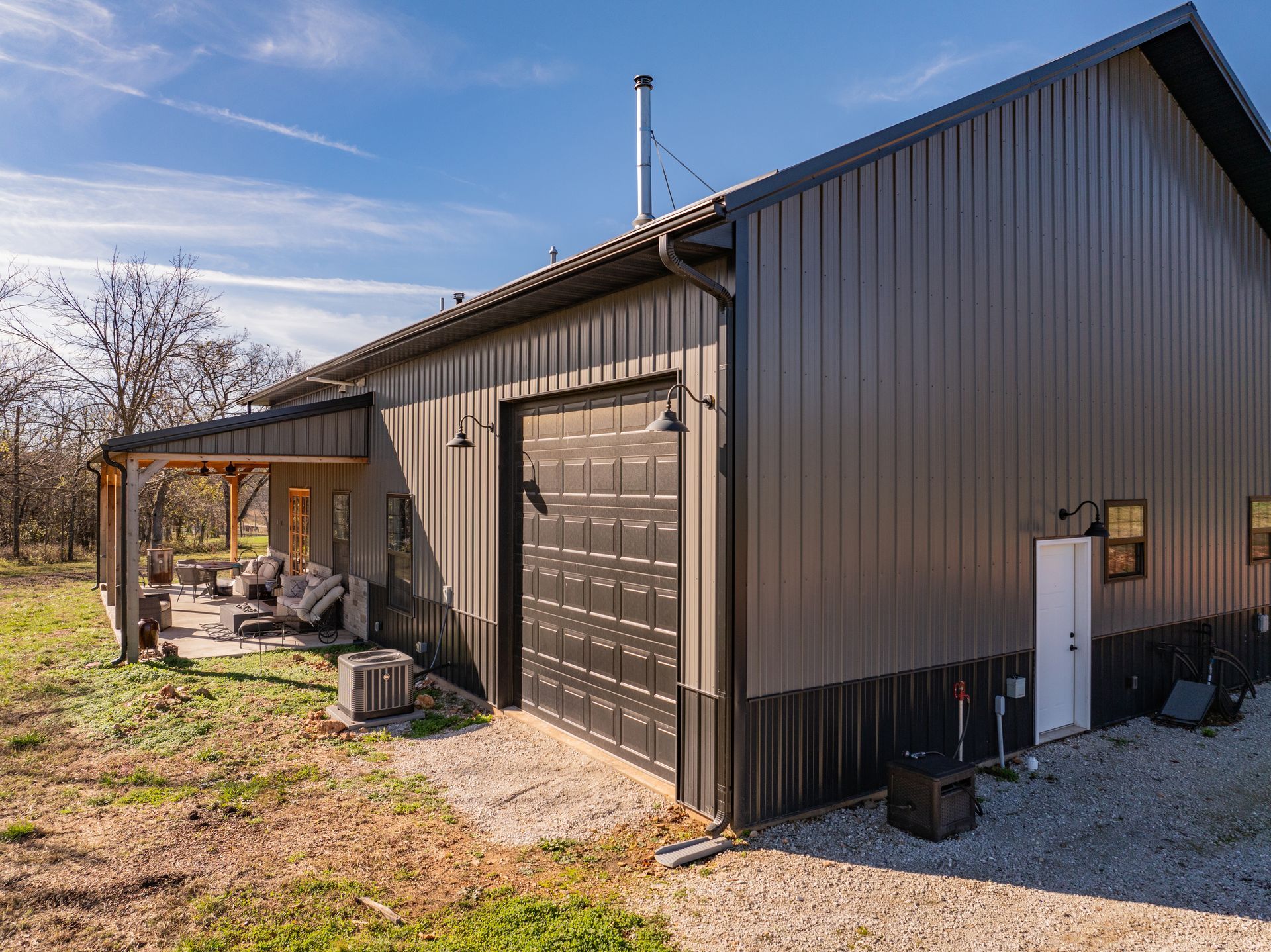 A large metal building with a garage door and a porch.