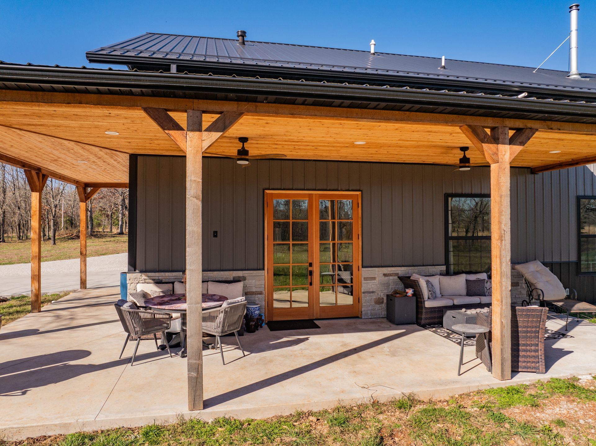 A covered patio with a table and chairs in front of a house.