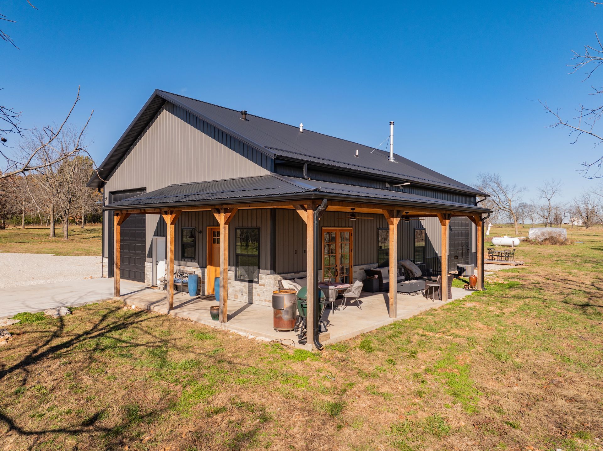 A large house with a porch in the middle of a field.
