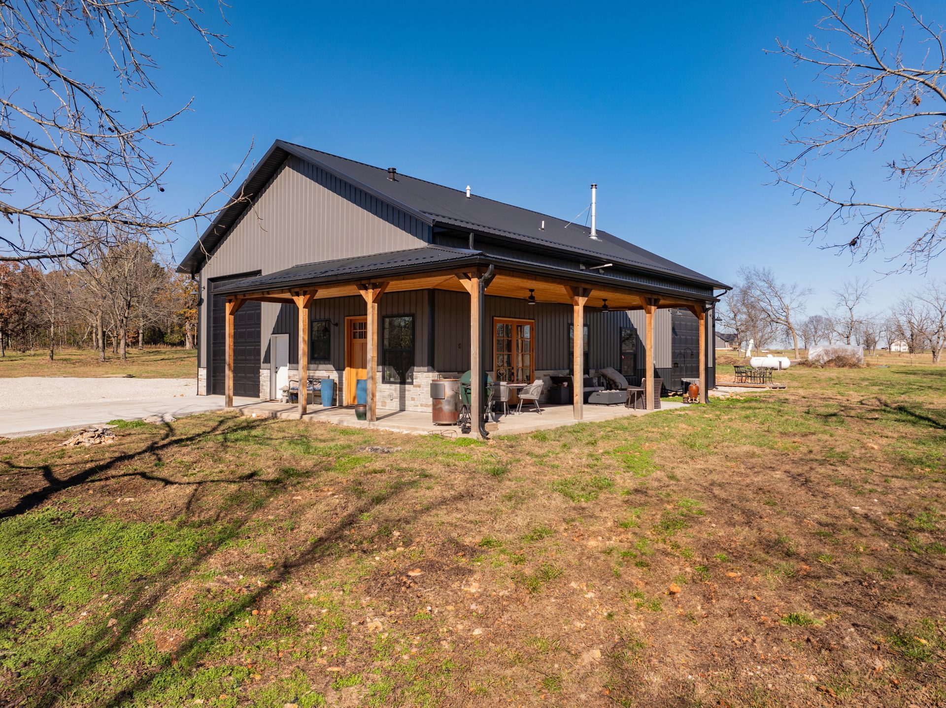 A small house with a porch in the middle of a field.