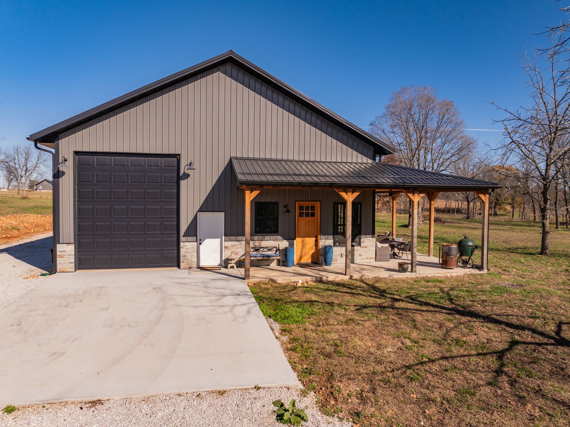 A large metal building with a porch and a garage door.