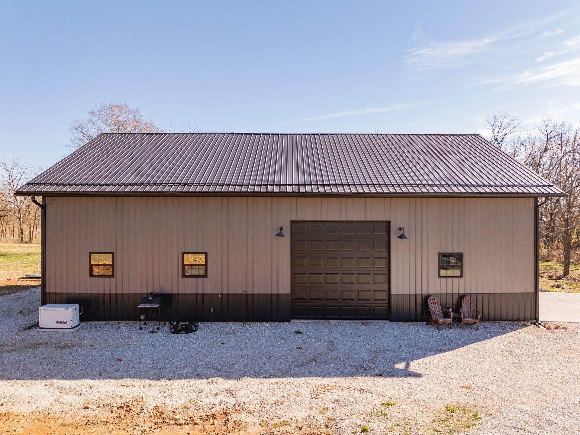 A large brown and black building with a garage door and windows.