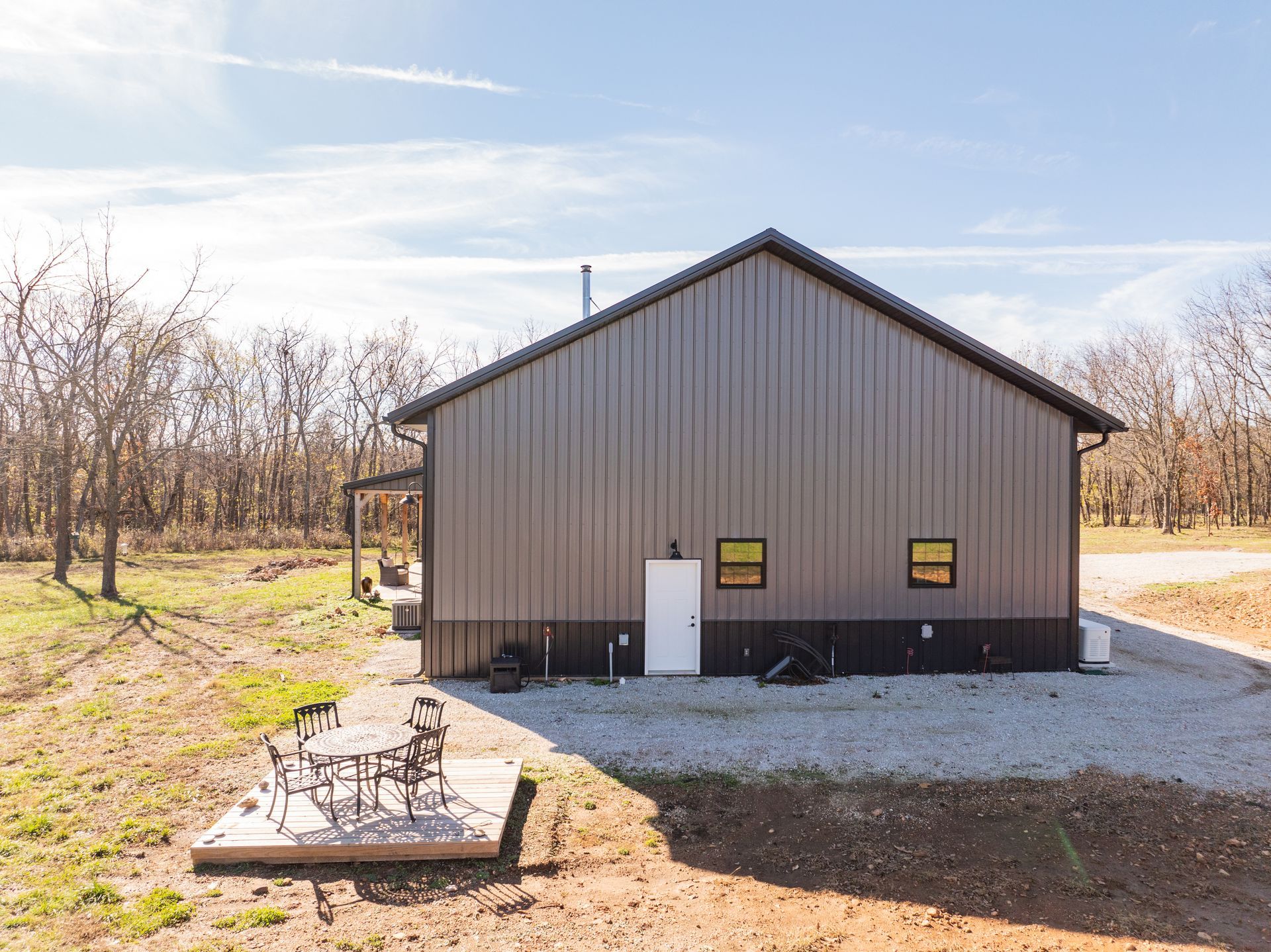 A large metal building with a porch and a table and chairs in front of it.