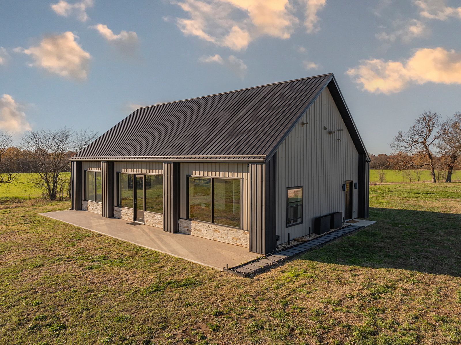 A small house is sitting in the middle of a grassy field.