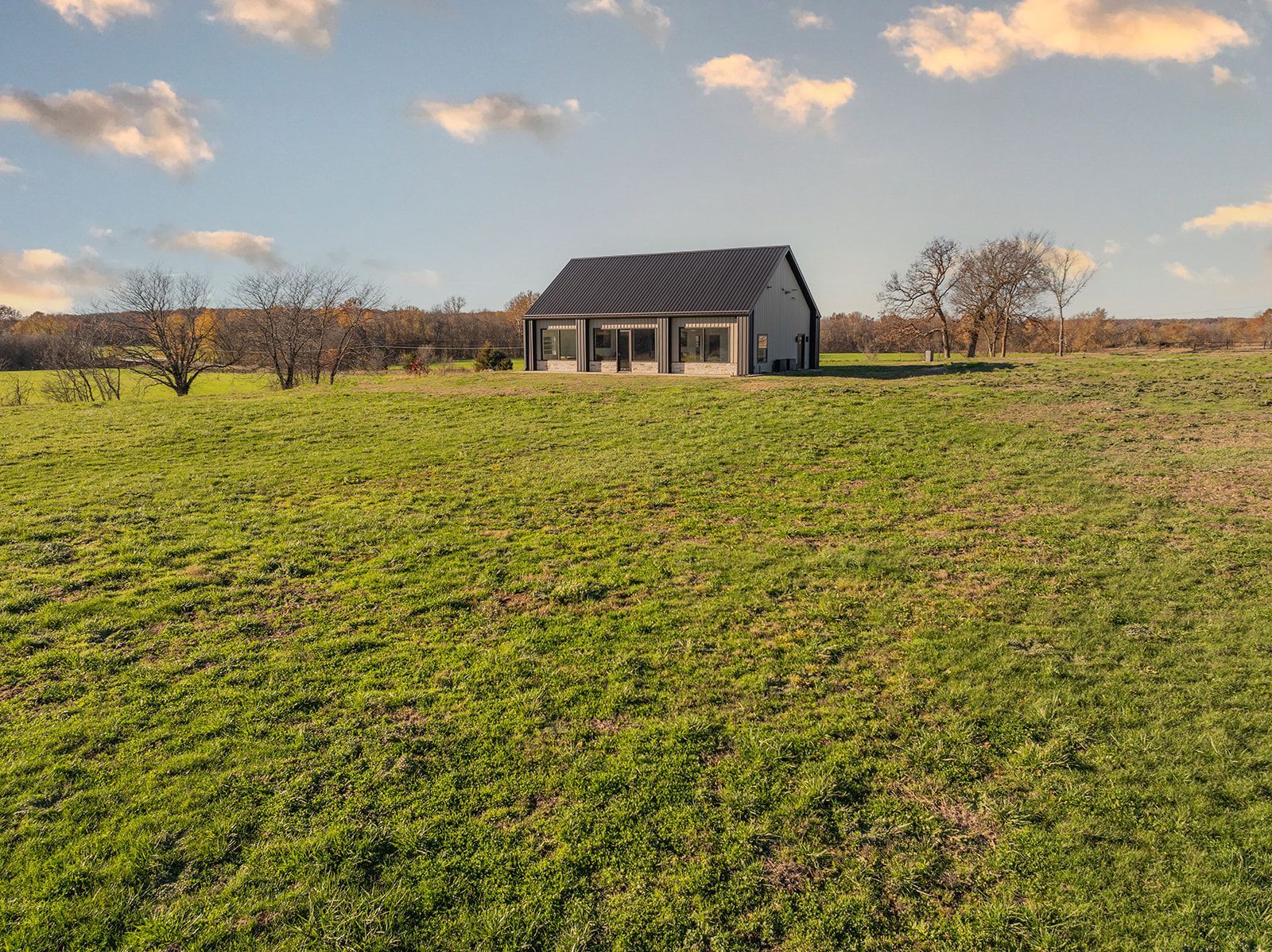 A small house is sitting in the middle of a lush green field.
