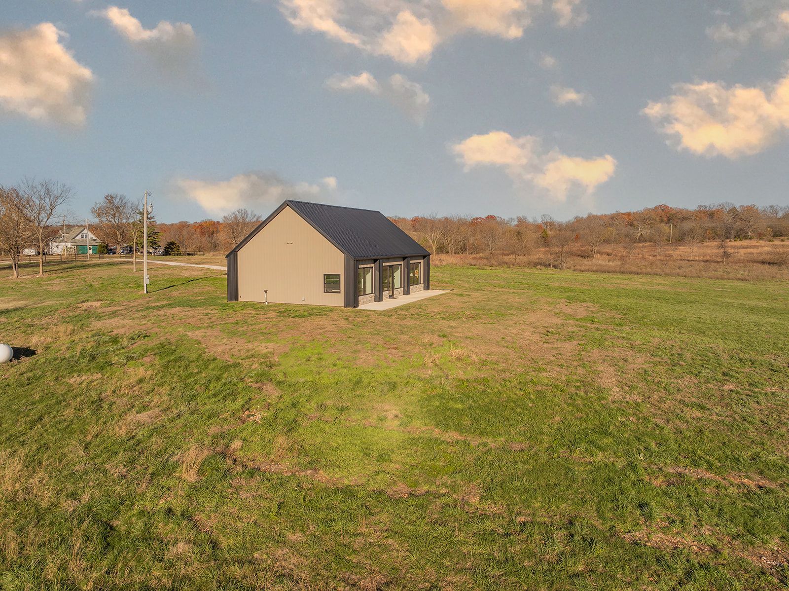 A small house is sitting in the middle of a grassy field.
