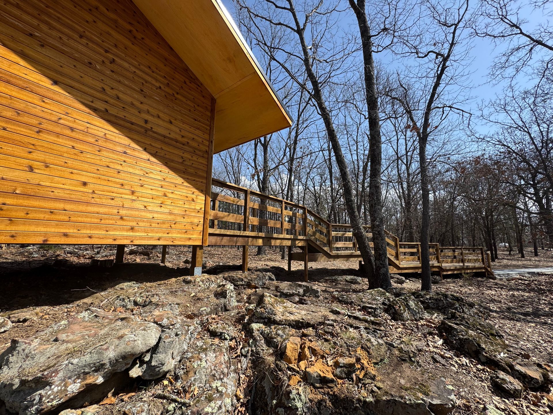 A wooden cabin with a wooden deck in the woods.