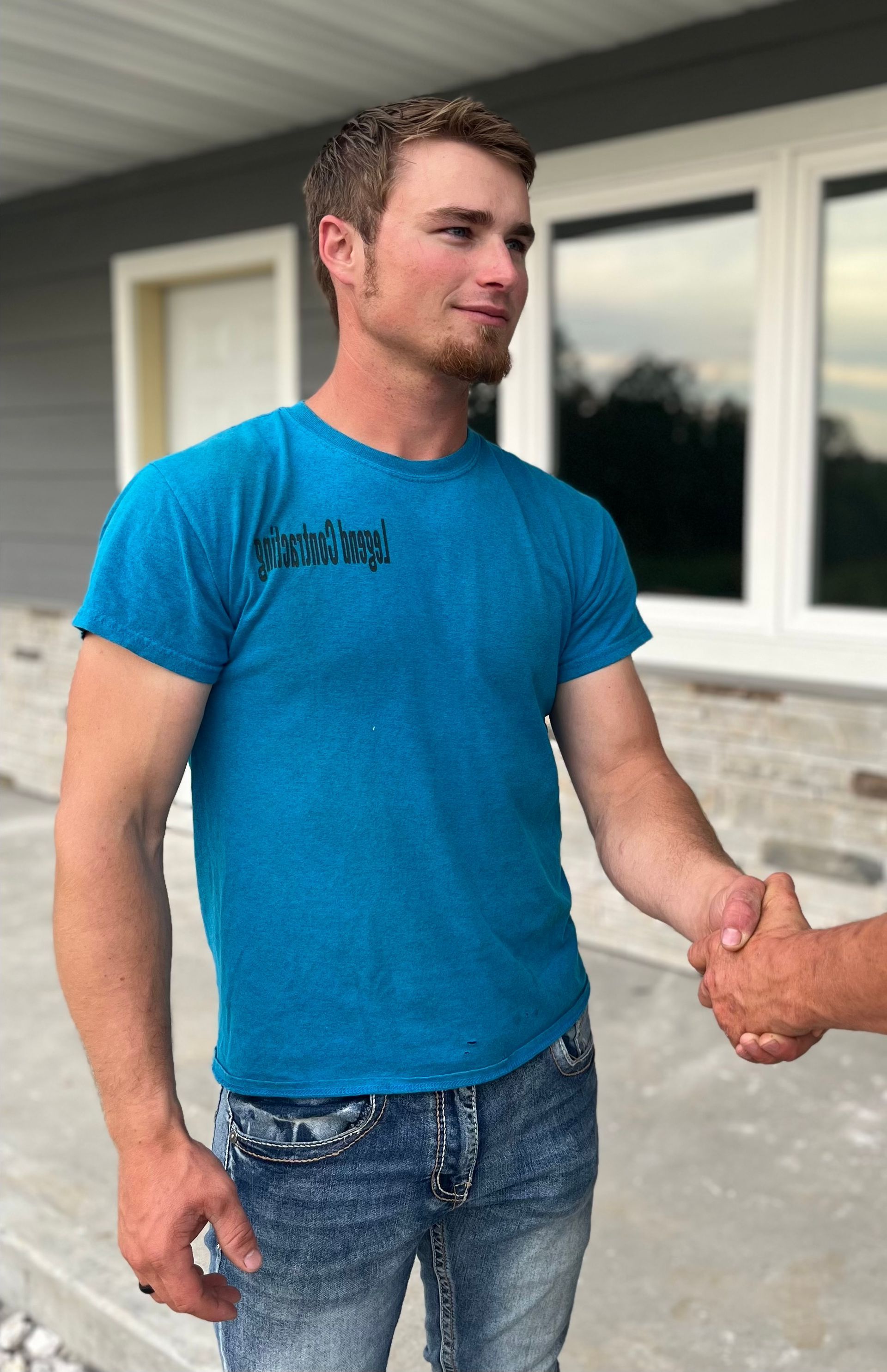 A man in a blue shirt is shaking hands with another man.