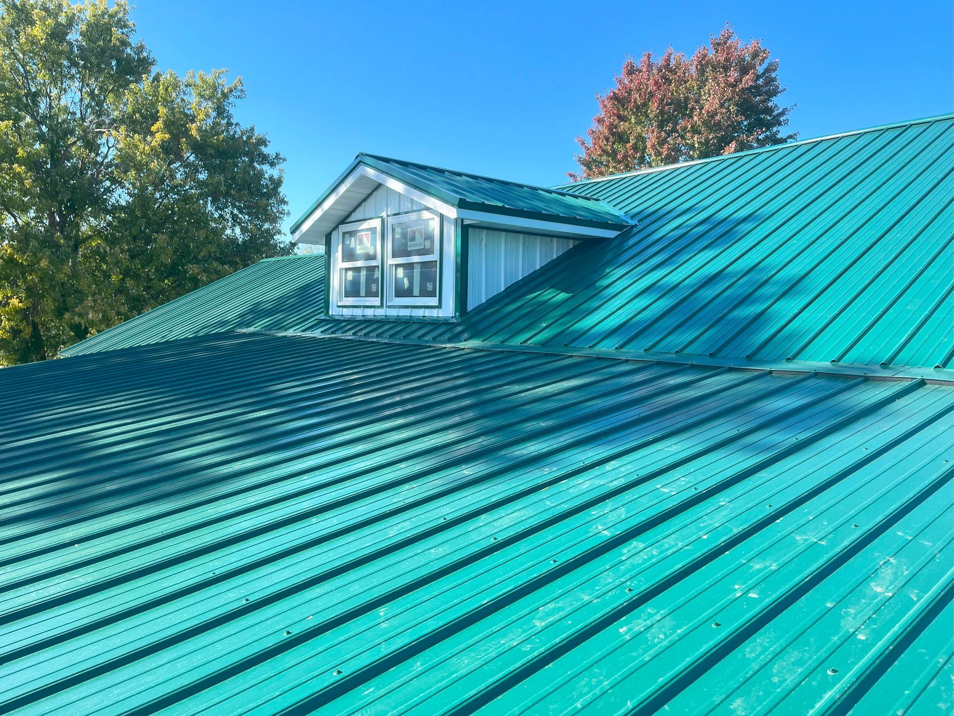 A green metal roof with a window on top of it.