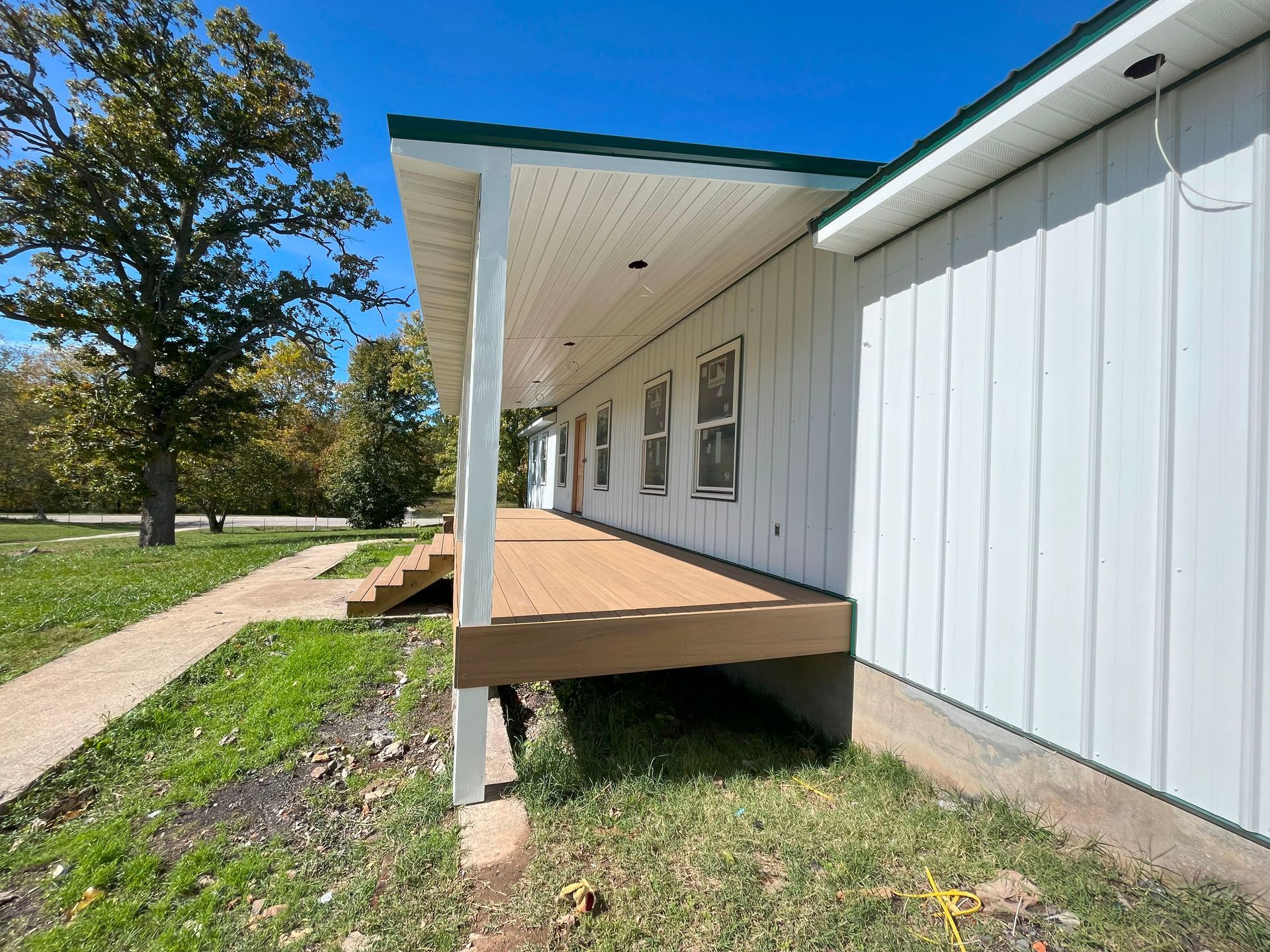 A white house with a porch and a wooden deck.
