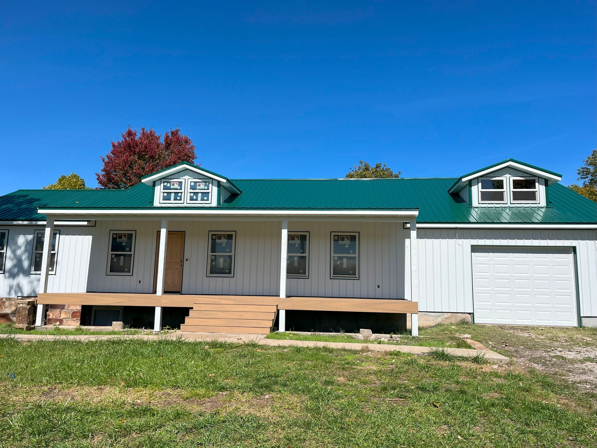 A white house with a green roof and a garage