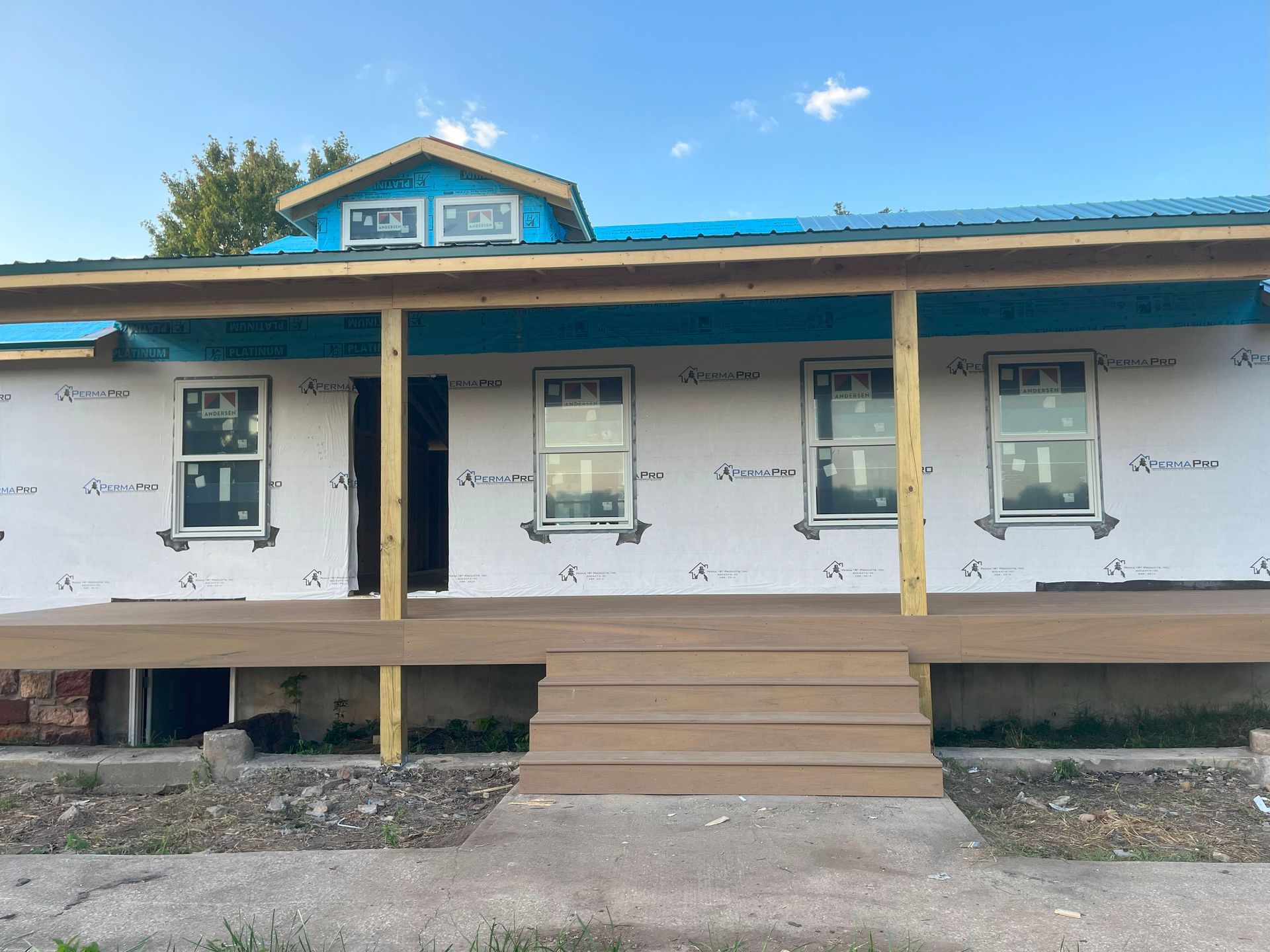 A house under construction with a blue roof and a porch