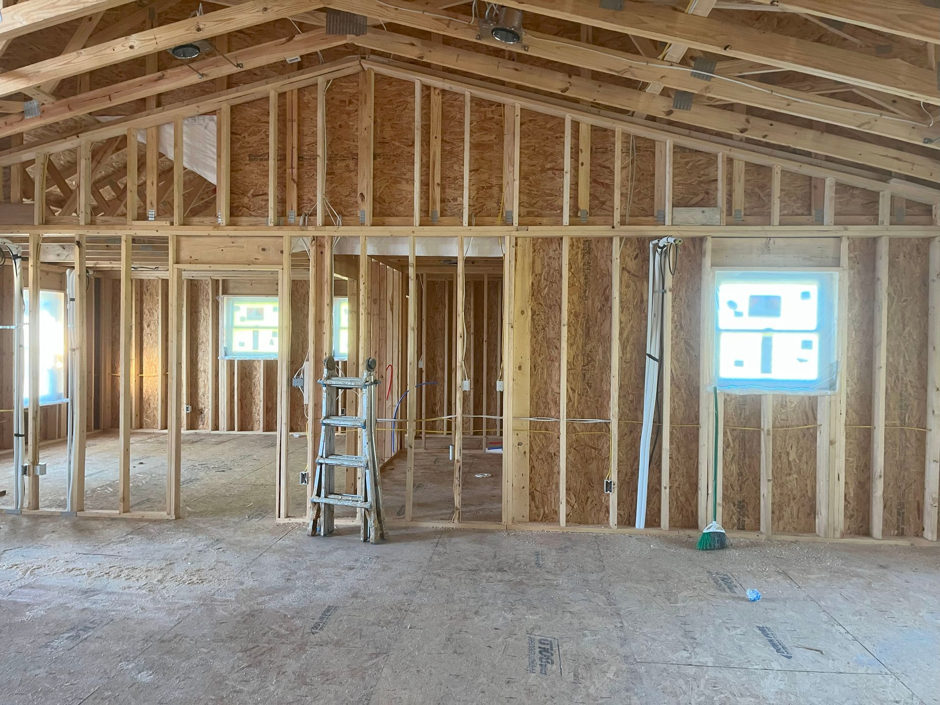 A ladder is sitting in the middle of a room in a house under construction.