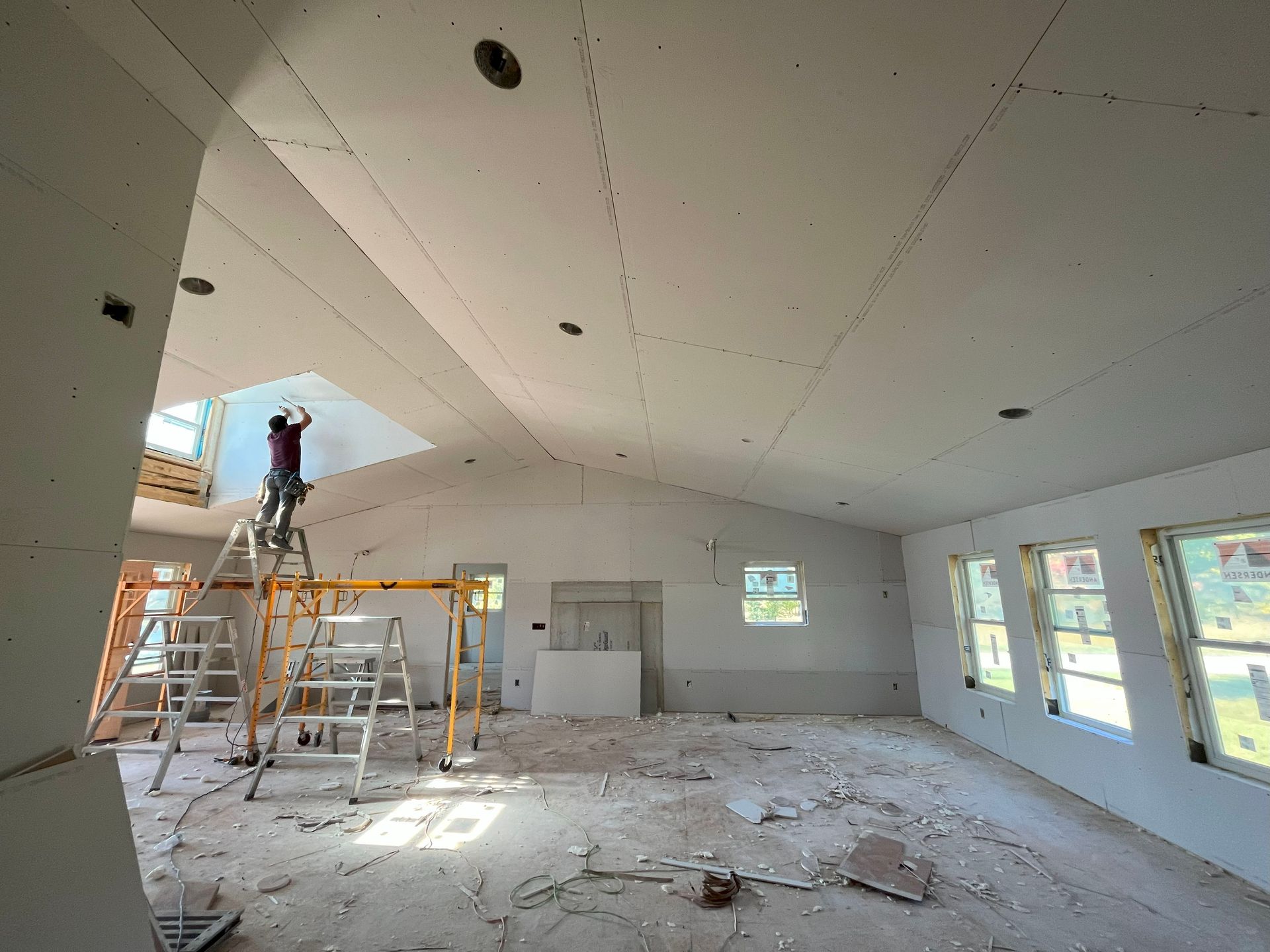 A man is standing on a ladder in an empty room.