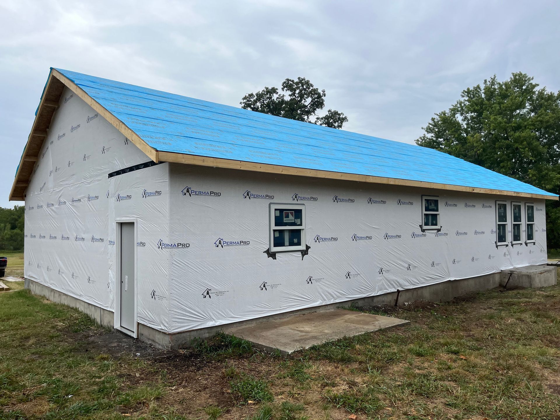 A white house with a blue roof is being built.