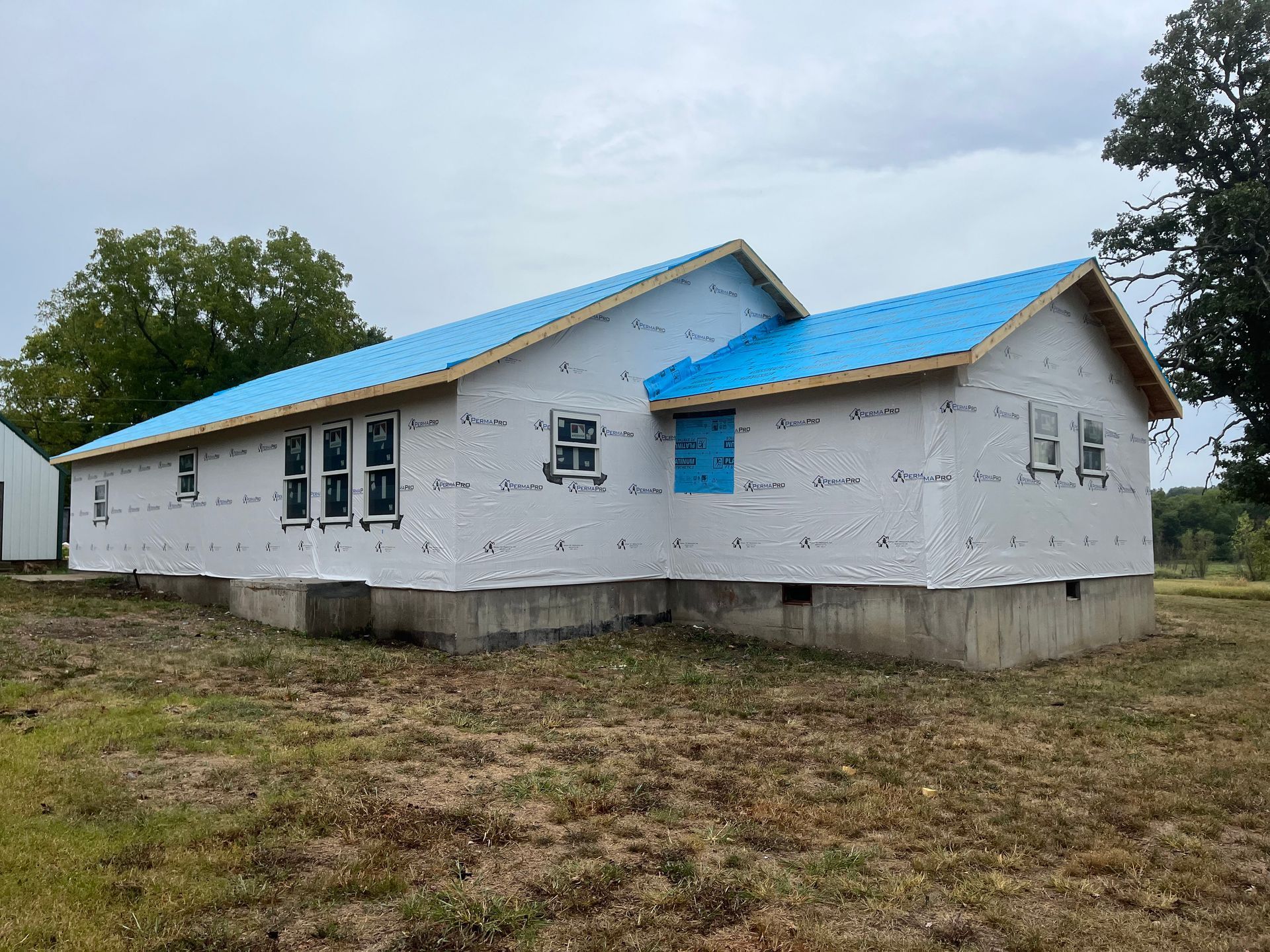 A white house with a blue roof is being built in a field.