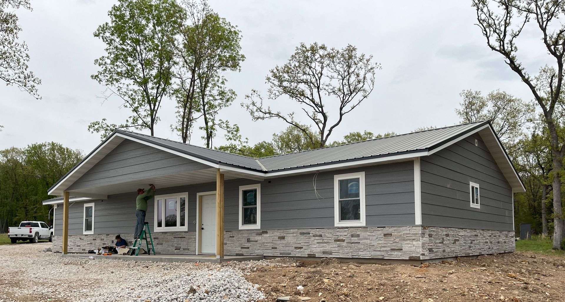 A gray house is being built in the middle of a forest.