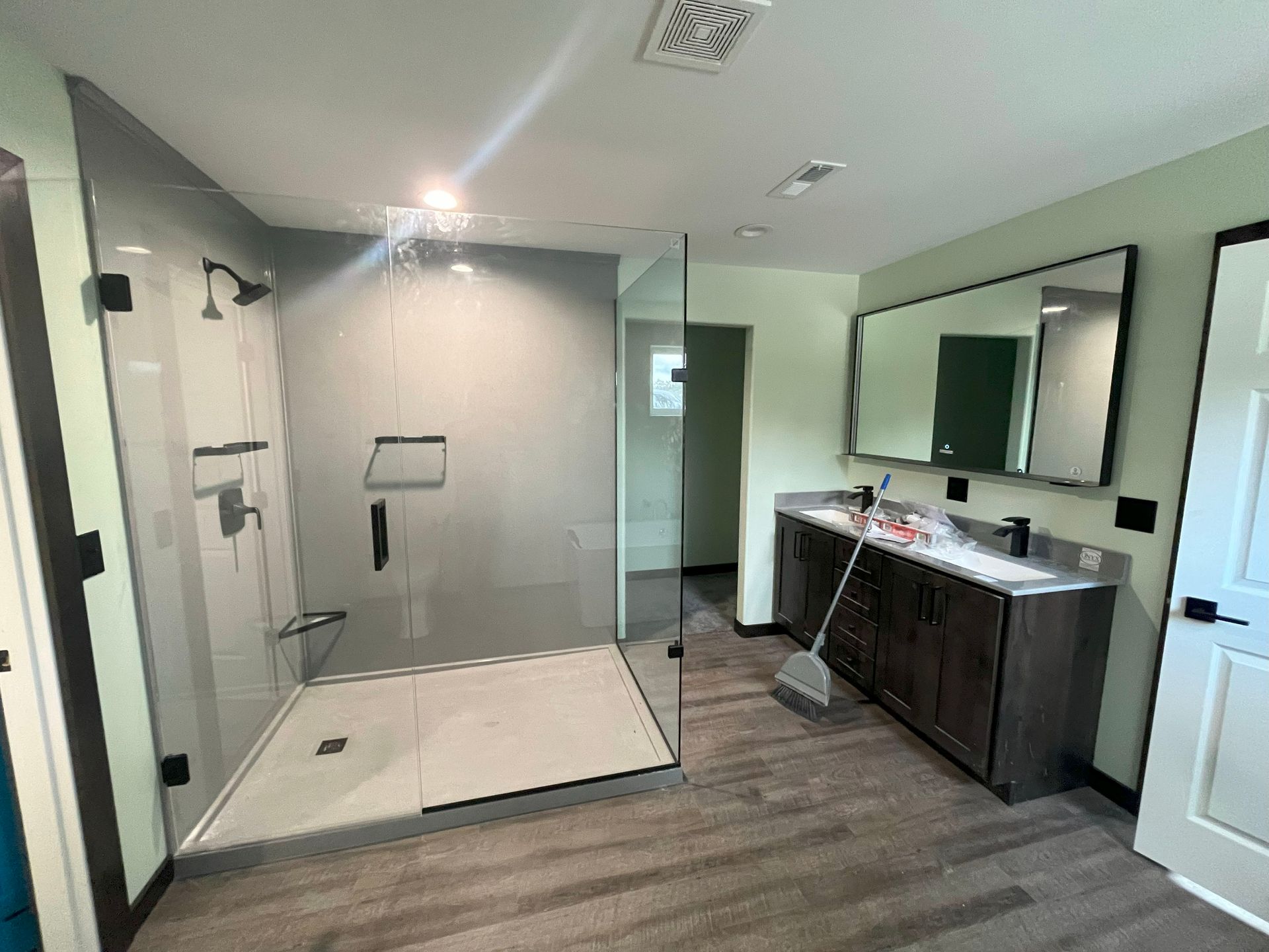 A bathroom with a walk in shower , sink and mirror.