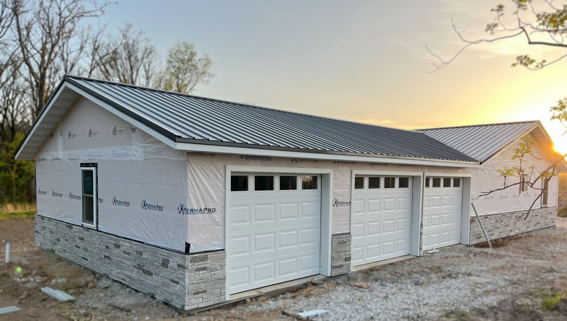A garage under construction with three garage doors and a roof.