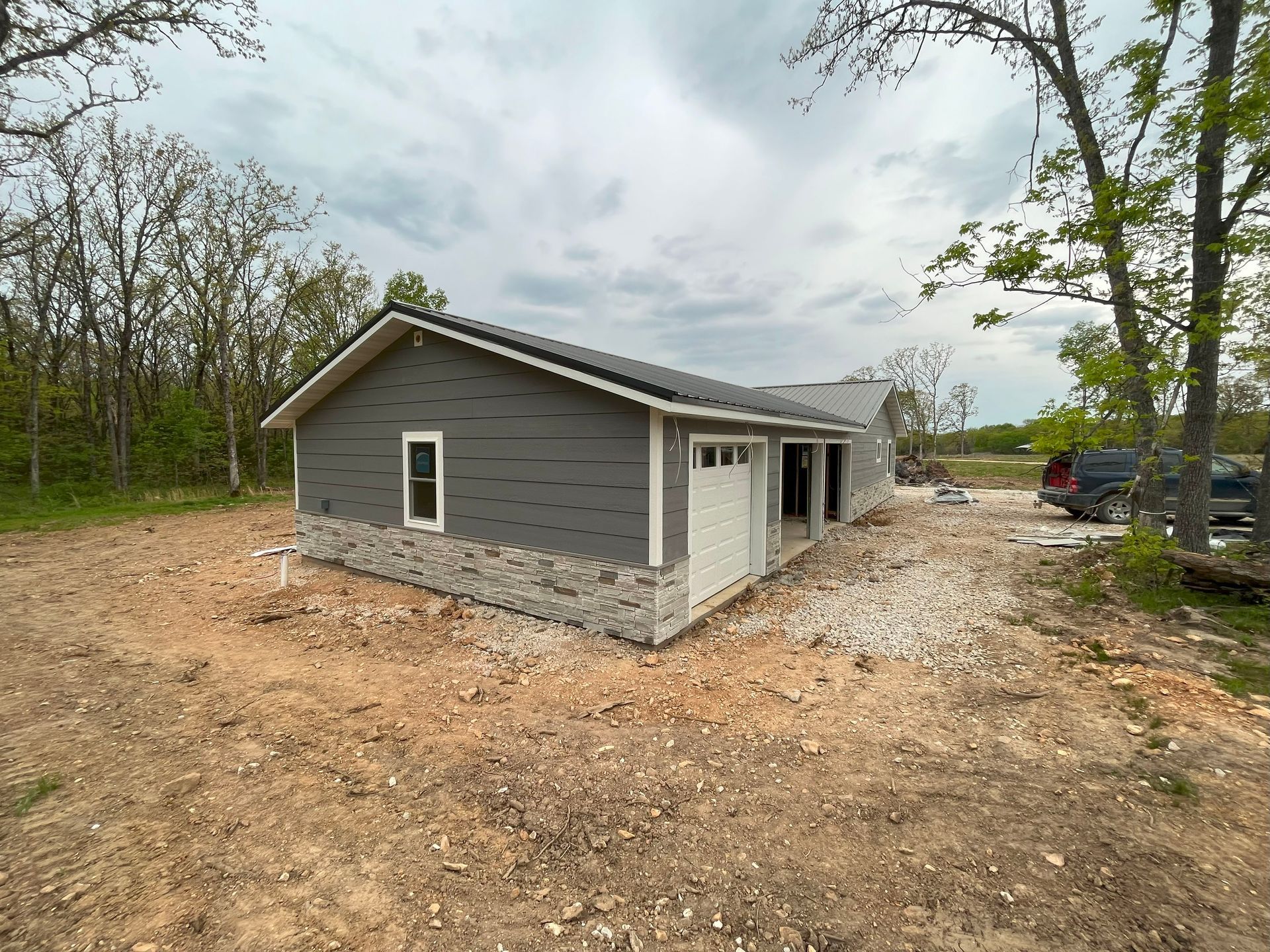 A small house is being built in the middle of a dirt field.